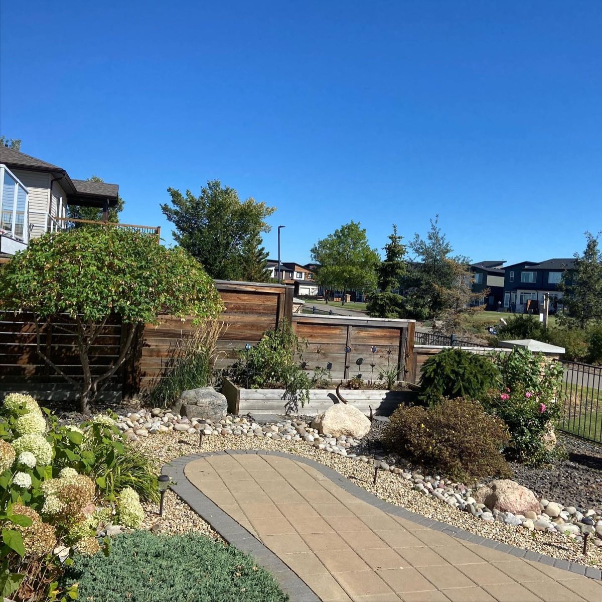 Dry river-rock garden with a curving paver path and layered planting