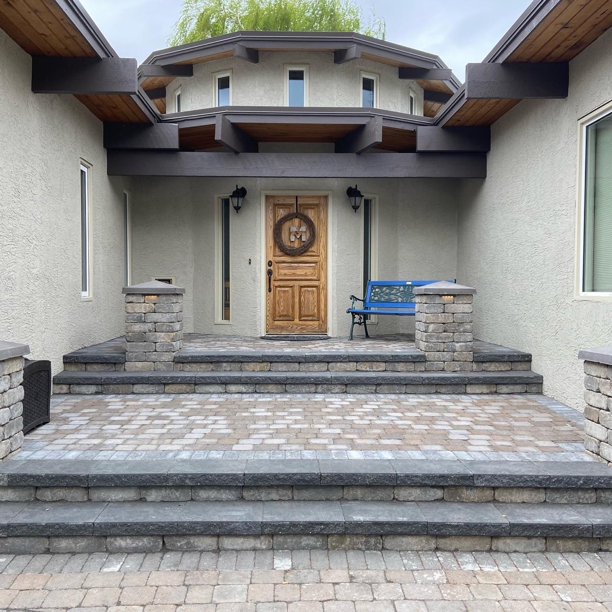 A paver entrance with stacked-stone pillars and wide stone steps
