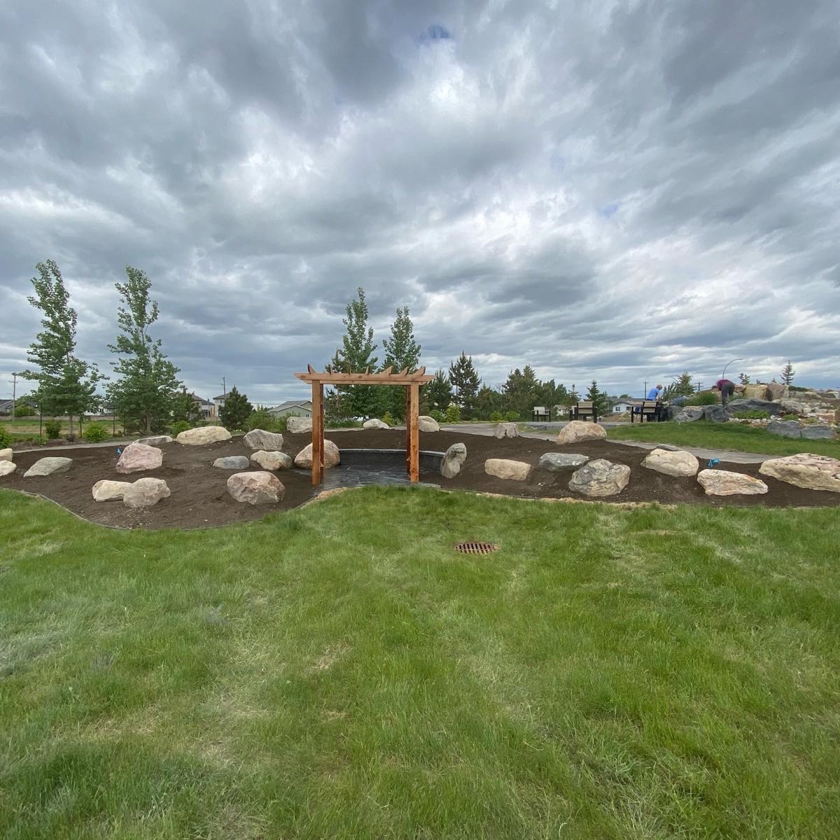 Boulder garden and cedar arbor under a wide prairie sky