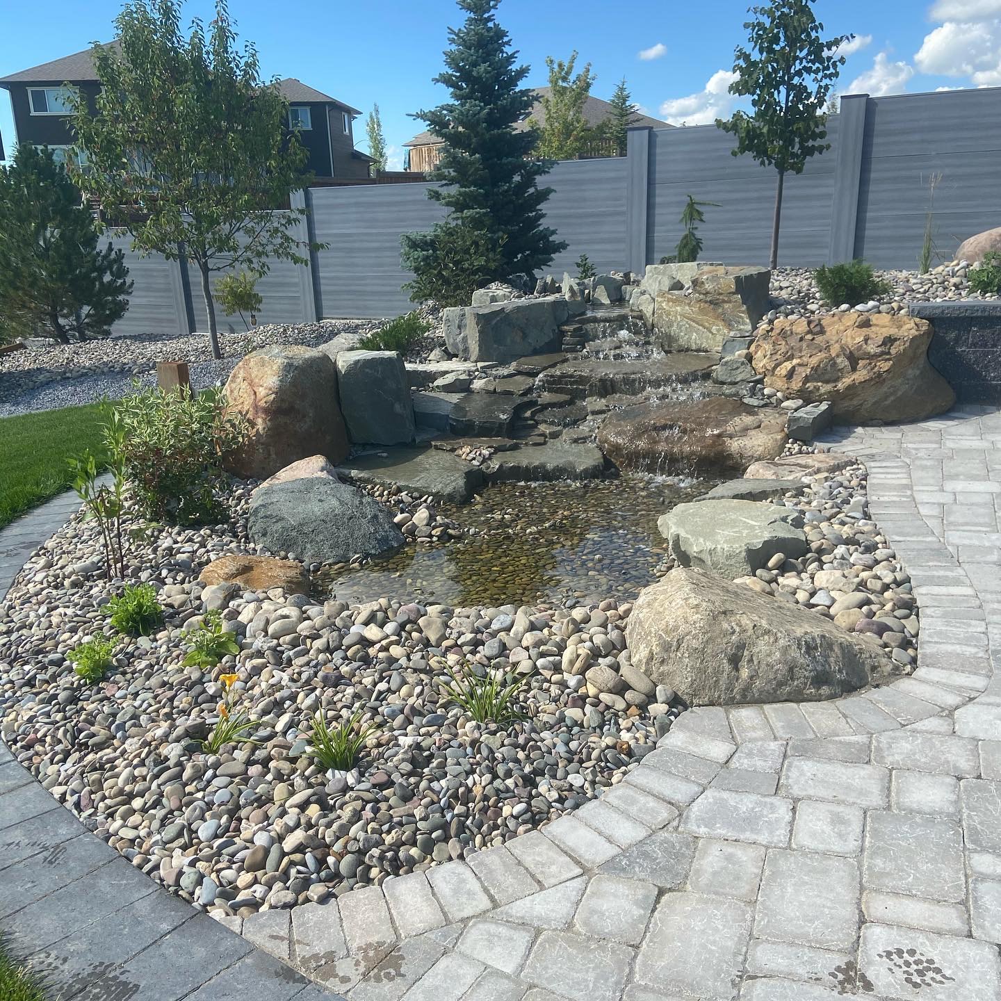 A stacked-stone waterfall and river-rock pond built by Southern Alberta Rock Gardens